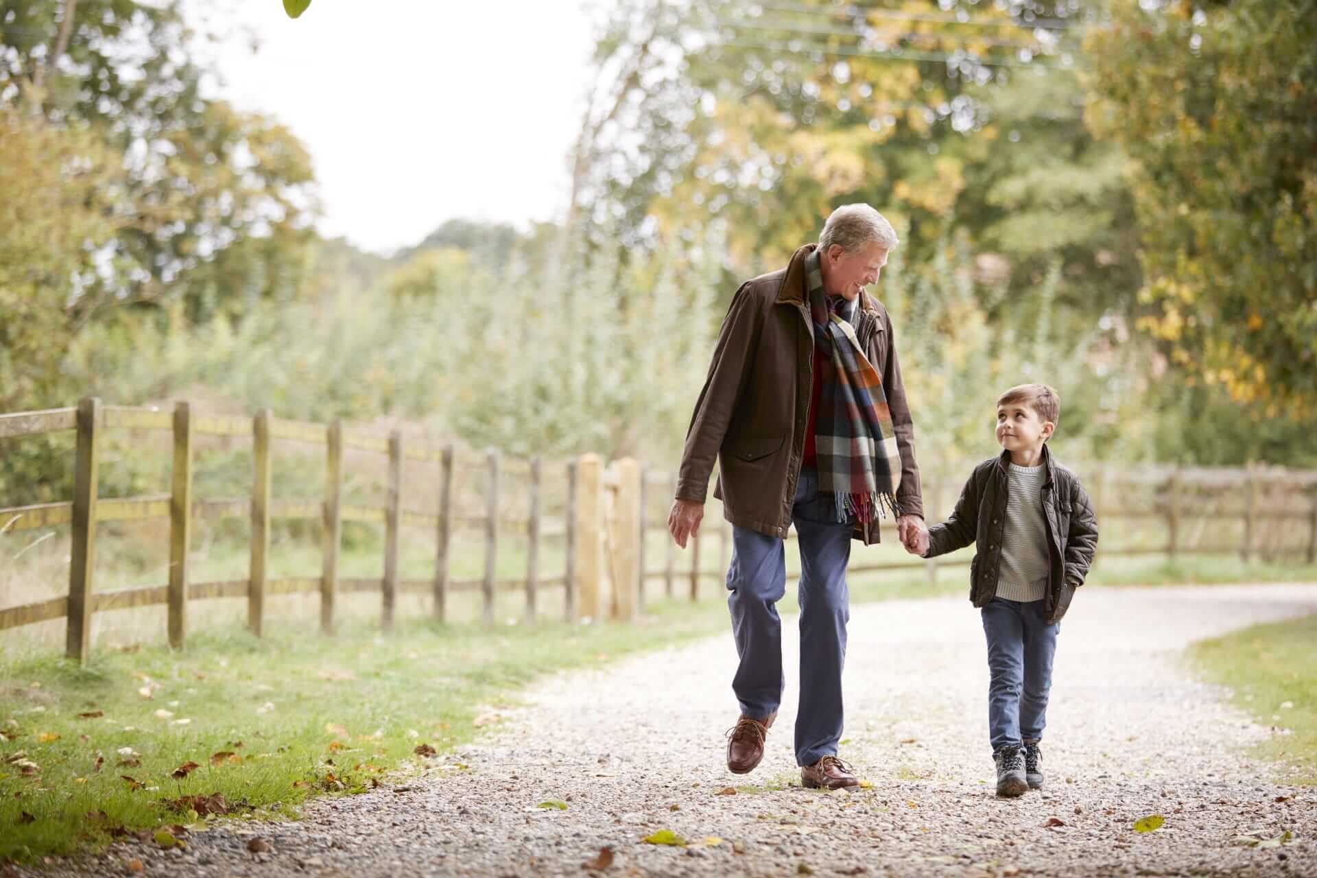 Grandfather and grandson holding hands on a countryside walk, benefits of private healthcare